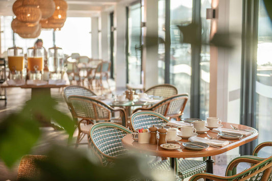 Chaises de bistrot en rotin tissé main, coloris sur mesure, dans la salle d'un établissement d'hôtellerie-restauration